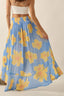 Woman wearing a blue floral skirt with yellow flowers on a plain background