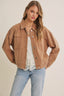Woman wearing a brown jacket over a white top and blue jeans on a beige background