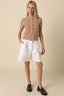 Woman wearing a striped shirt and white shorts on a beige background
