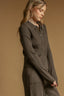 Woman wearing a brown ribbed sweater and pants against a beige background