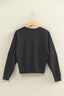Black sweatshirt on a wooden hanger against a beige wall