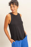 Woman wearing a black sleeveless top and blue pants against a beige background