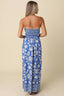Woman wearing a blue floral strapless dress against a beige background