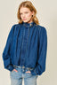 Woman wearing a blue denim jacket and jeans on a beige background