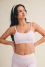 Woman wearing a light pink checkered sports bra and leggings on a beige background