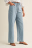 Light blue denim pants worn by a person on a beige background