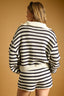 Person wearing a black and white striped outfit on a beige background