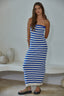 Woman wearing a blue and white striped dress against a white wall.