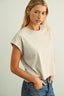 Woman wearing a beige t-shirt and blue jeans against a plain background