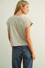 Woman wearing a light gray t-shirt and blue jeans against a plain background