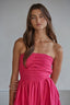 Woman wearing a pink strapless dress against a plain background