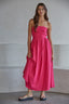 Woman wearing a pink strapless dress standing against a plain background