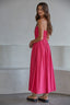 Woman wearing a pink dress standing against a plain background