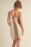 Woman wearing a color-blocked dress with beige, green, and white stripes on a neutral background