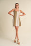 Woman wearing a two-tone dress with beige and white colors on a plain background