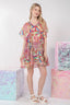 Woman wearing a colorful dress standing next to patterned boxes on a white background
