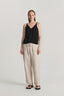 Woman wearing a black sleeveless top and beige pants on a white background