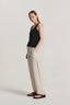 Woman wearing a black sleeveless top and beige pants on a white background
