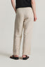 Person wearing beige pants and black sandals on a plain background
