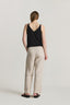 Person wearing a black tank top and beige pants on a plain background