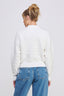 Person wearing a white sweater and blue jeans on a plain background