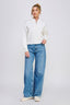 Woman wearing a white blouse and blue jeans on a light gray background