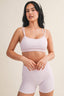 Woman wearing a matching lavender sports bra and shorts set on a beige background