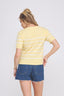 Woman wearing a yellow striped shirt and denim shorts on a white background