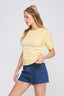 Woman wearing a yellow striped shirt and blue denim shorts on a white background