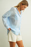 Woman wearing a light blue shirt and white shorts against a plain background