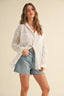 Woman wearing a white shirt and denim shorts on a beige background