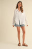 Woman wearing a white shirt and denim shorts on a beige background