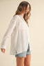 Woman wearing a white oversized shirt and denim shorts on a beige background