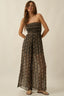 Woman wearing a strapless, long, patterned dress against a plain background