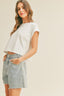 Woman wearing a white crop top and light blue jeans against a beige background