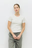 Person wearing a white t-shirt and gray pants against a plain background