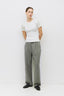 Person wearing a white t-shirt and green pleated pants on a white background
