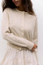 Woman wearing a beige and white striped sweater against a white background