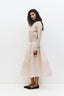 Woman wearing a beige sweater and skirt against a white background