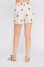 Person wearing a white skirt with palm tree pattern on a plain background