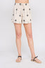 Person wearing cream shorts with black palm tree pattern on a white background
