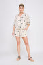 Woman wearing a matching shirt and shorts set with palm tree pattern on a white background