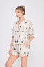 Woman wearing a matching top and shorts set with palm tree pattern on a white background