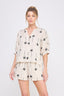 Woman wearing a cream-colored outfit with black palm tree pattern on a white background