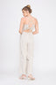 Woman wearing a white striped jumpsuit with cut-out design on a white background