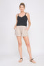 Woman wearing a black tank top and beige shorts on a white background