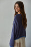 Woman wearing a blue knitted sweater against a plain background