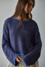 Woman wearing a blue knitted sweater against a gray background