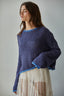 Woman wearing a blue knitted sweater with a plain background