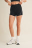 Person wearing black athletic shorts on a beige background